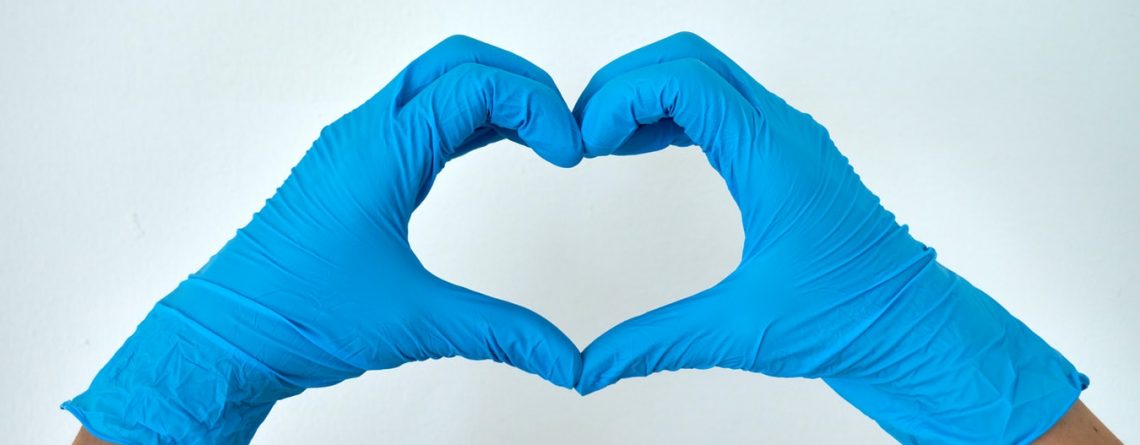 two hands wearing disposable gloves making a heart shape