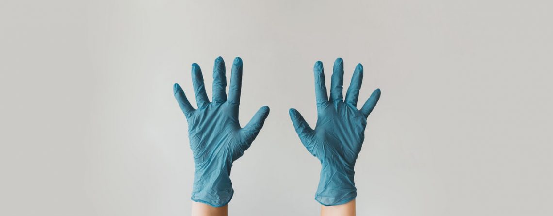 two hands in blue disposable gloves raised upright