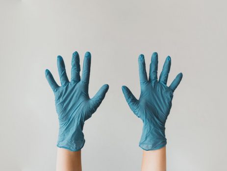two hands in blue disposable gloves raised upright